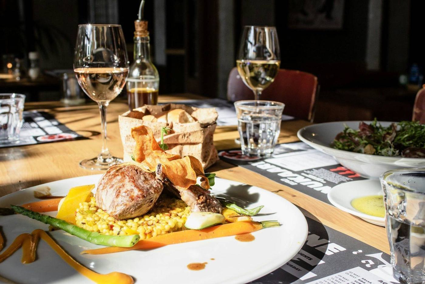 A restaurant table laid with plates, glasses and cutlery